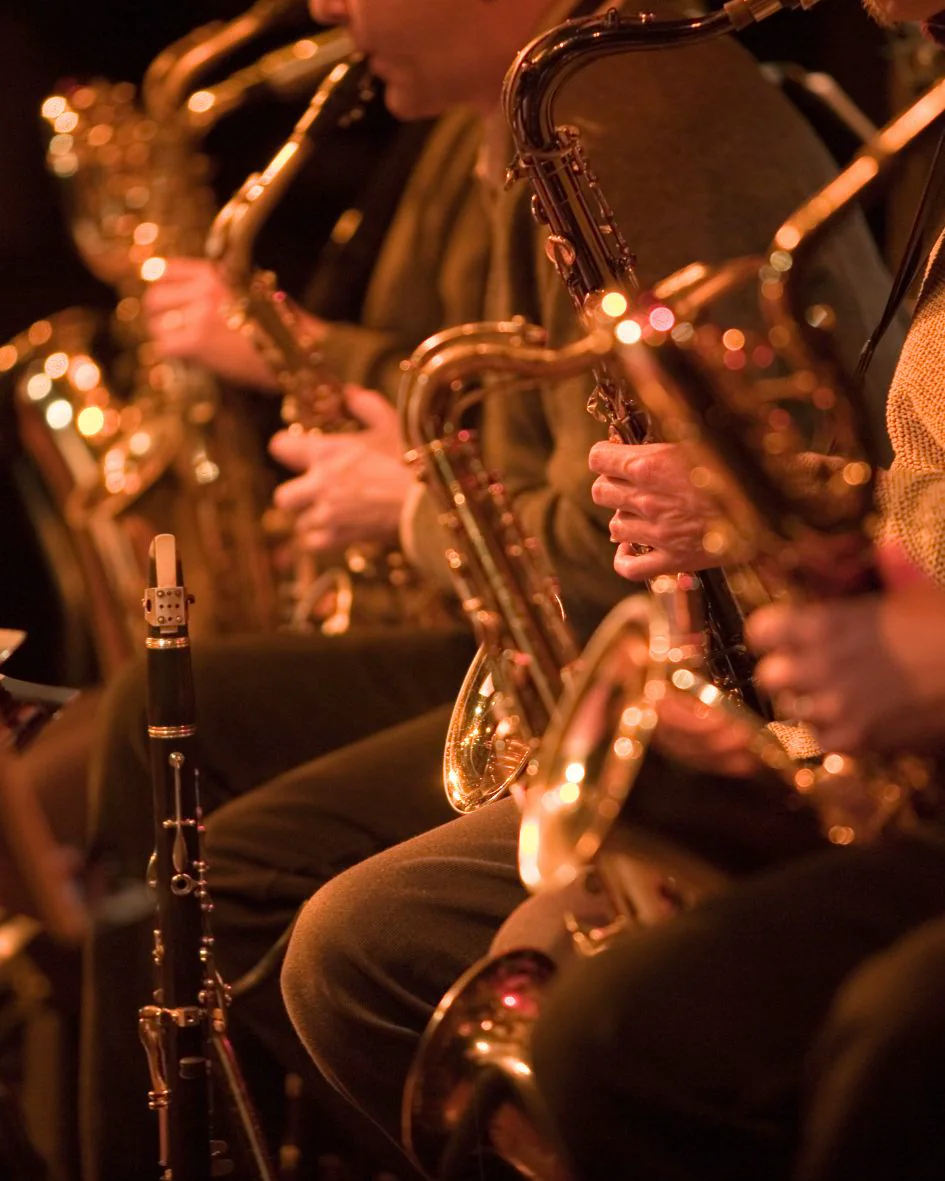 Saxophonists performing together under warm stage lighting